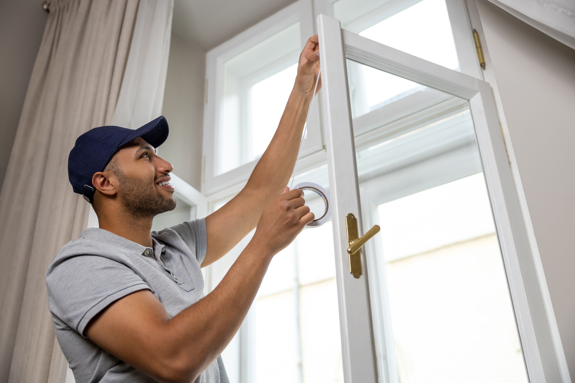 Man putting sealing foam tape on window indoors insulating his house.